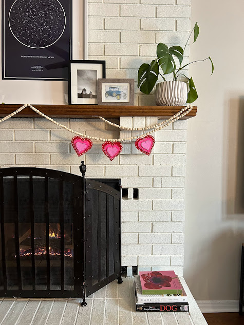 Valentines Day garland craft hanging from a white brick fireplace.