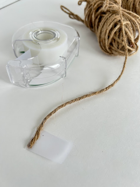 Using scotch tape to wrap the tip of the string for easy threading through the beads.
