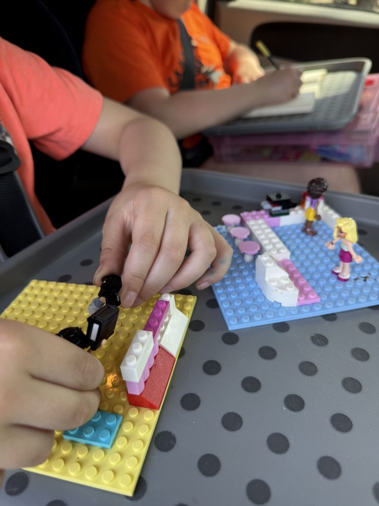 Child driving in a car playing with lego on a lap tray