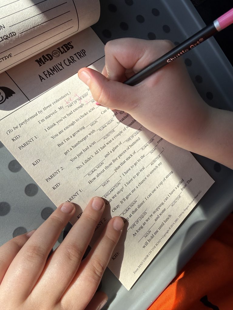 Child writing in an activity book while travelling in a car