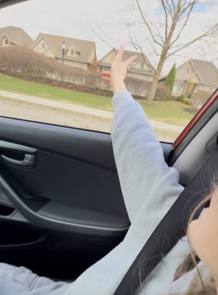 Screenshot Child driving with hand out the window feeling the wind